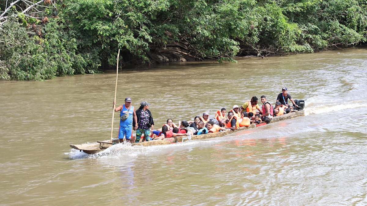 20 people in a wooden canoe on a river.