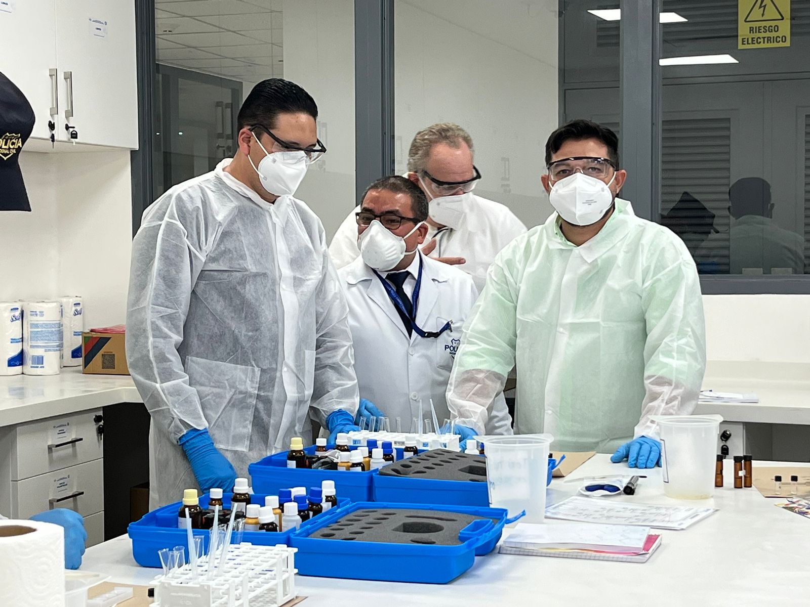 Participantes en taller sobre nuevas sustancias psicoactivas ofrecido por UNODC utilizando batas en un laboratorio.