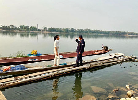 Woman standing on a long Kanu on a river talking to a man