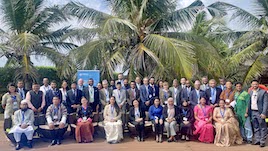 A group photo taken outside. In the background, the roll up banner of the Global Programme on Implementing the Organized Crime Convention and palm trees. 