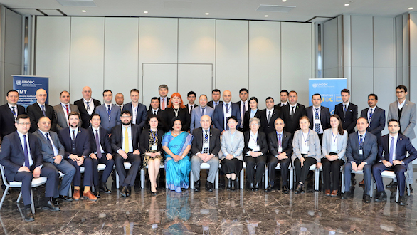 A group photo of the participants of the conference taken inside a room. In the back, banners with words "Implementing UNTOC" and "UNODC Regional Office for Central Asia" are visible.