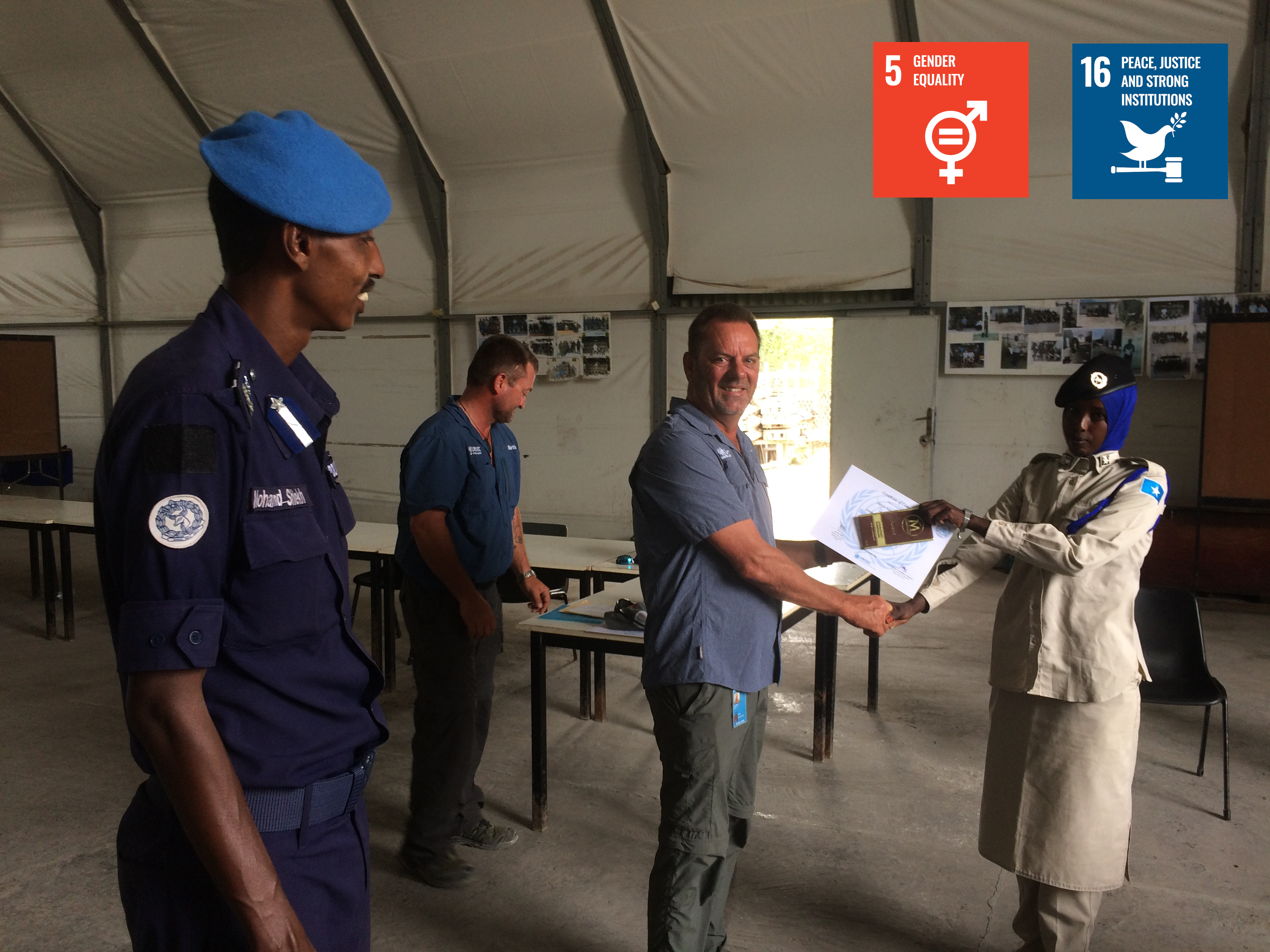 UN Officials handing a young women officer a certificate. The logos of SDG 5 and SDG 16 are featured in the corner. 