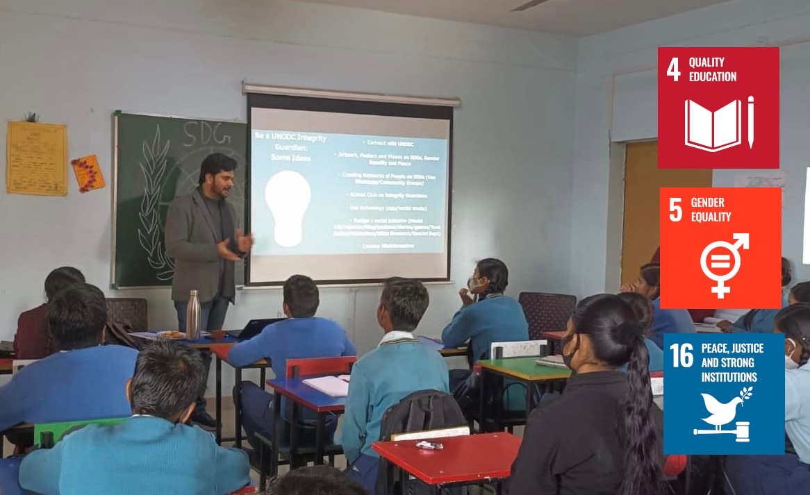 A teacher in Indian leading a session on integrity education with students in desks sitting around. The logos of SDG 4, SDG 5 and SDG 16 are also featured on the right side. 