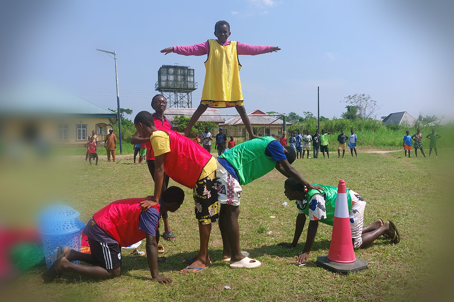Youth making a human pyramid in a grassy field in Nigeria. 