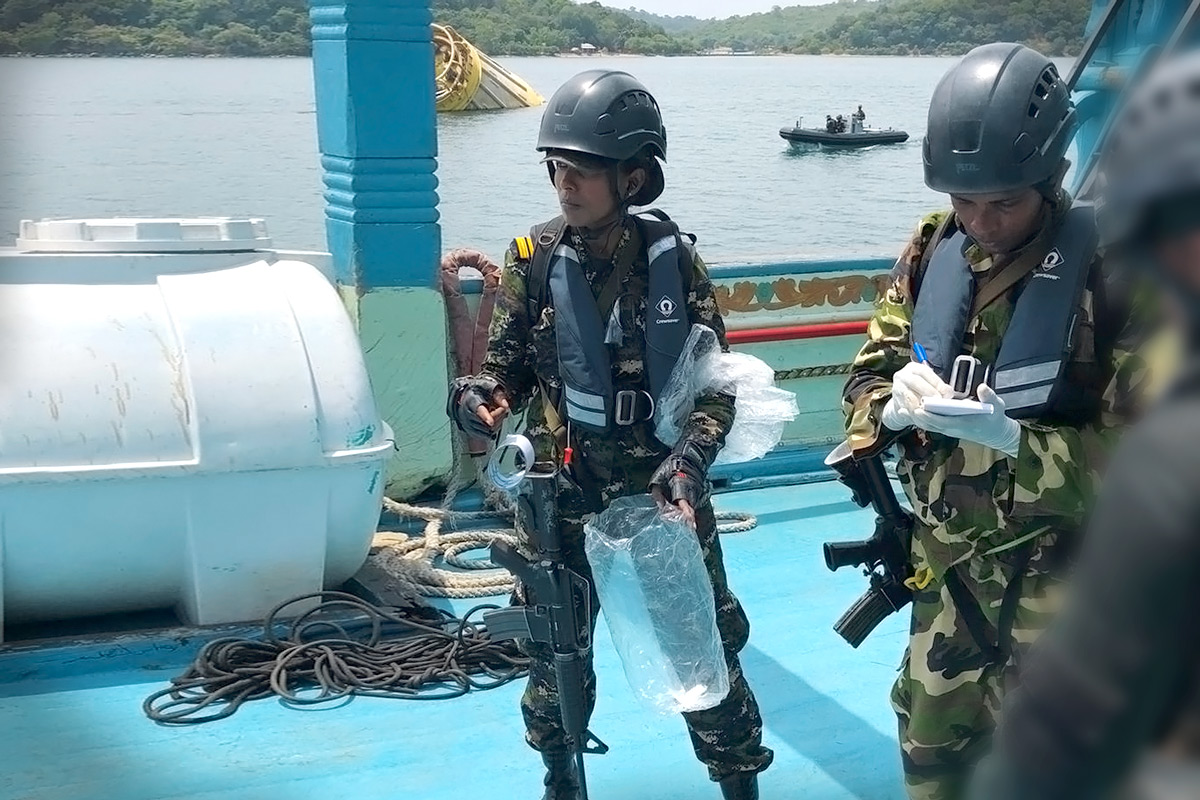 One female and two male law enforcement officers aboard a ship.