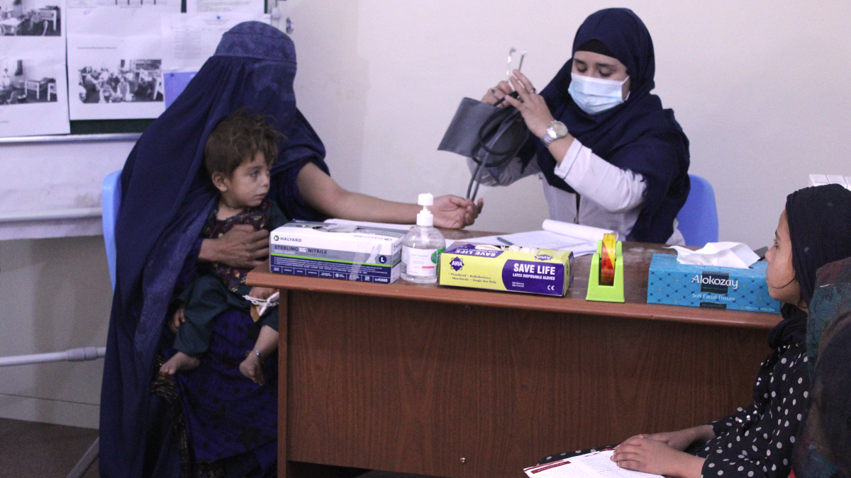 A health worker preparing to attach a blood pressure cuff to a woman’s outstretched arm at the Youth Health and Development Organization in Afghanistan.