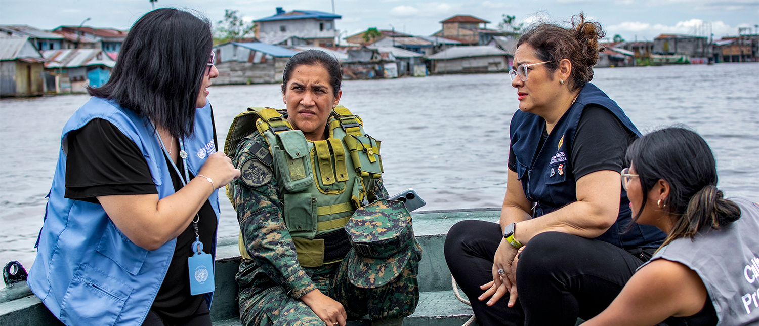 Four women in diverse uniforms discussing in a boat.