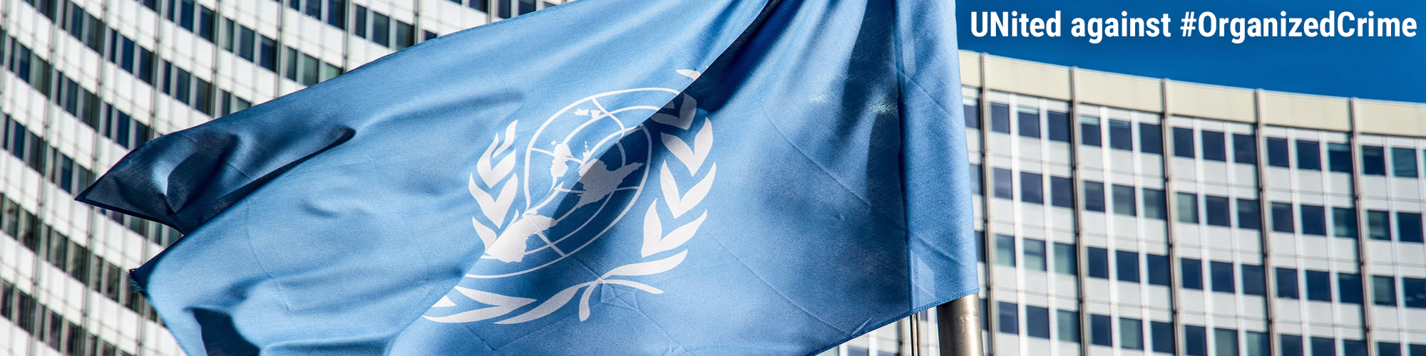 A visual with the flag of the United Nations. In the background the Vienna International Centre. The following text appears: UNited against #OrganizedCrime.