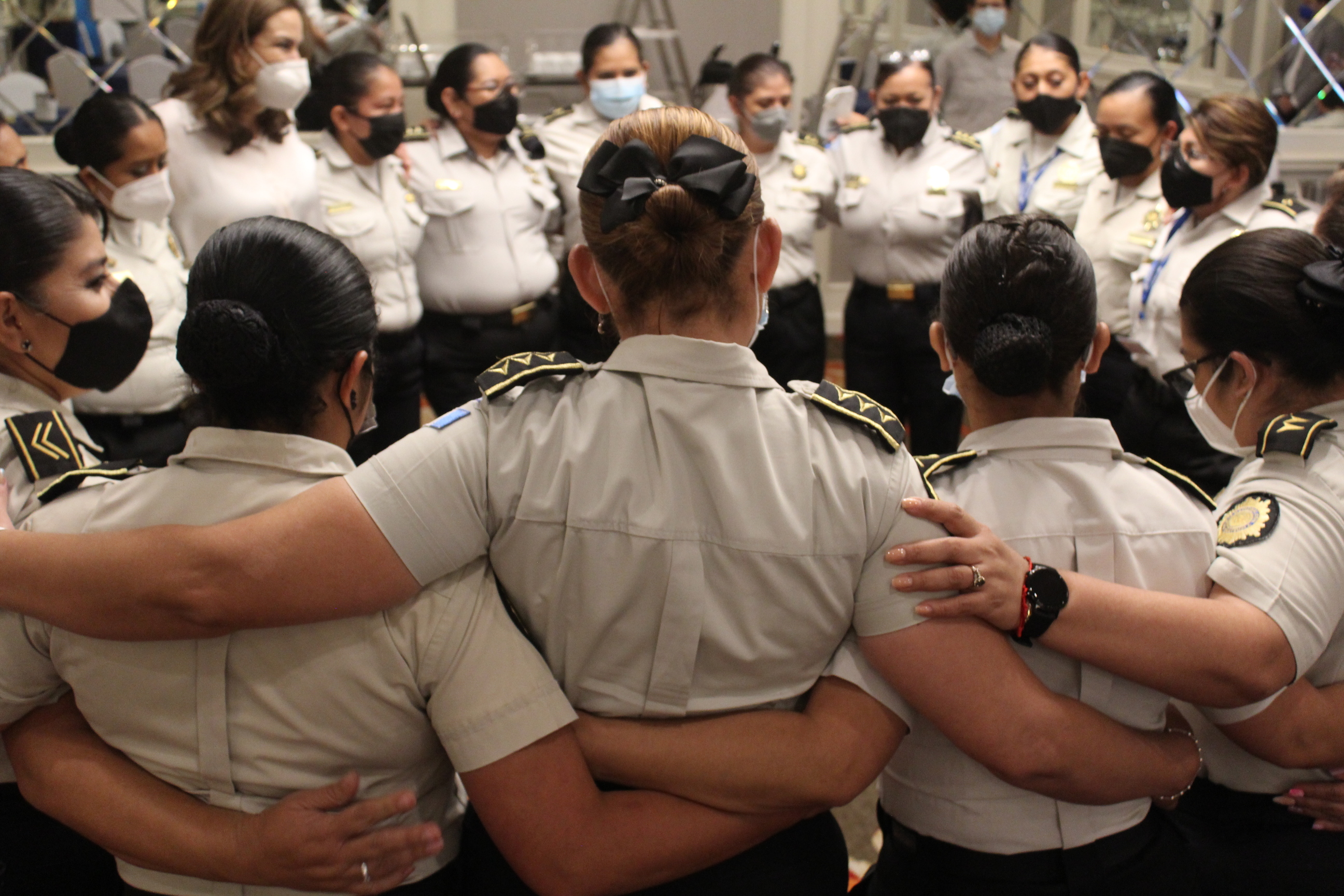 Grupo de mujeres policías abrazadas en círculo participando en un taller ofrecido por UNODC.
